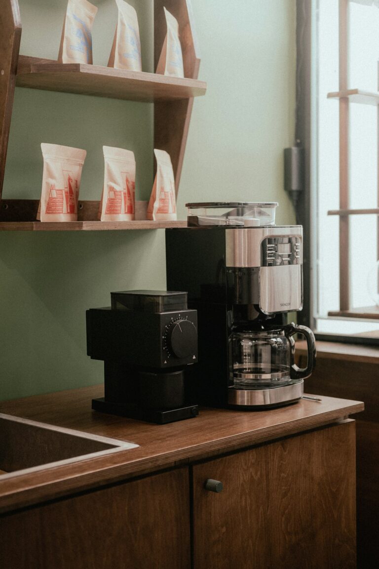 A person choosing between a burr and blade coffee grinder on a modern kitchen counter.
